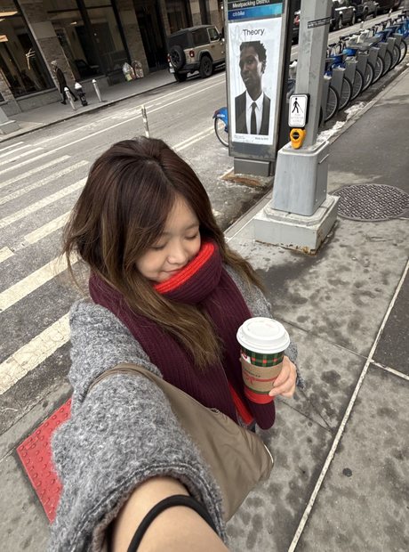 Orey on a New York street with a coffee, looking ahead.