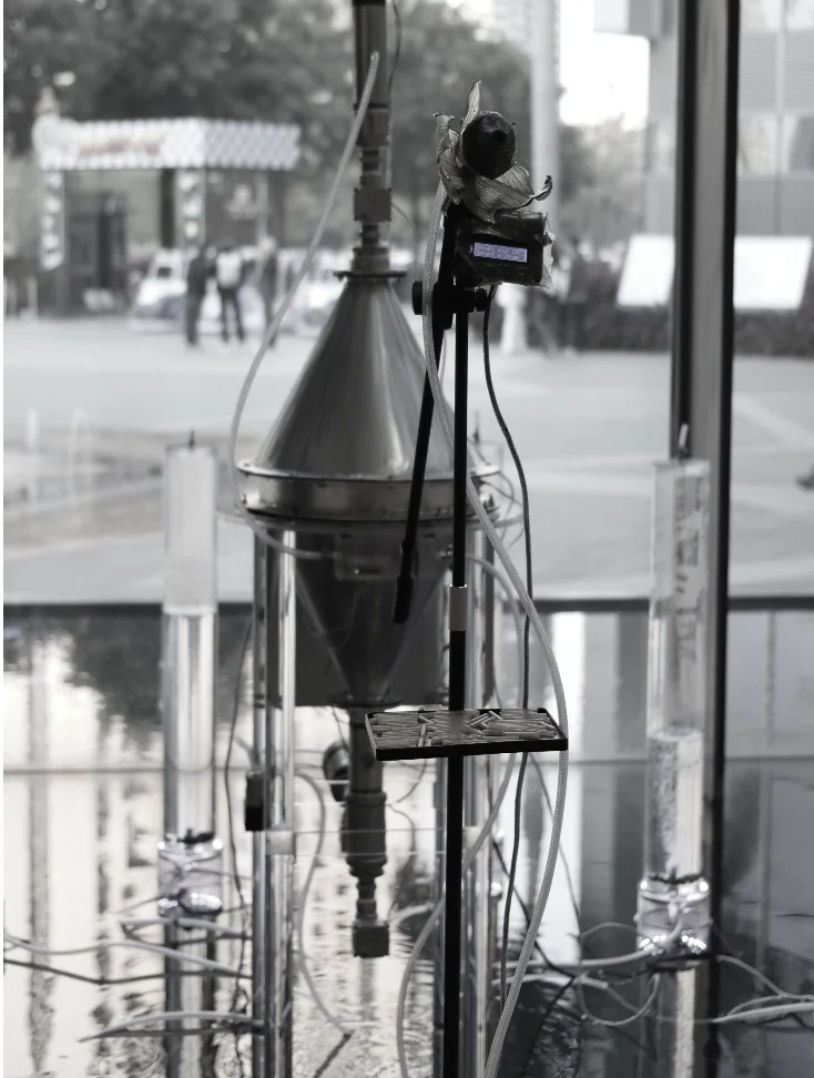 Black and white: the breath microphone with its bioplastic ornament and LCD screen in front of the steel reactor.