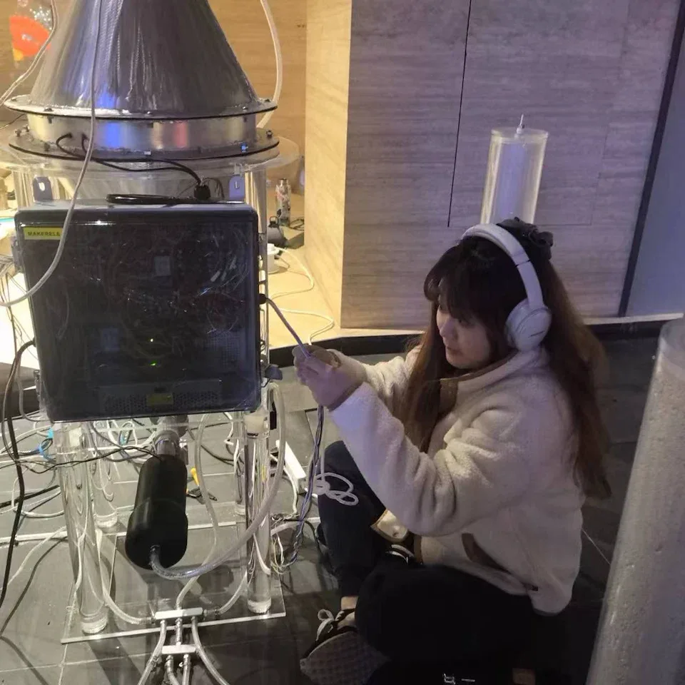 A team member wearing headphones, sitting on the floor and connecting cables to the control box under the reactor.